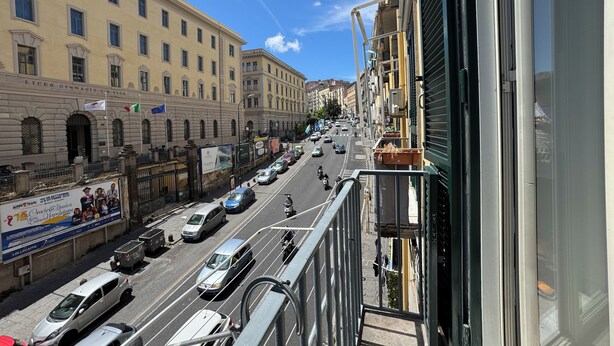 Vista de una calle con un edificio que dice 'Liceo Ginnasio G.Vico' y un cielo azul despejado.