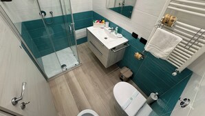 Un baño moderno con ducha de vidrio, un lavamanos blanco y un inodoro.