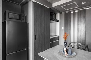 A modern kitchen with a built-in microwave, a stainless steel refrigerator, and a dining area with a table set for two. - GRAN HILLS 401 / Chitose City Hokkaidō (Chitose City)