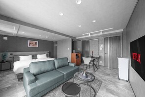 Une chambre d’hôtel moderne équipée d’un lit, d’un canapé, d’une table basse et d’un écran de télévision affichant le logo « NETFLIX ».