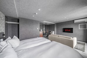 A modern hotel room with a large bed, a sofa, a desk with a chair, a flat-screen TV, and an air conditioning unit. - GRAN HILLS 405 / Chitose City Hokkaidō (Chitose City)