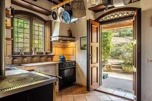 A kitchen with a stove, hanging pots, and a window with a view of greenery. - Apartment in Castel D'arno with 1 bedrooms sleeps 2 (Castel D'arno)