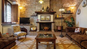 A cozy living room with a fireplace, stone walls, wooden beams, a television, and comfortable seating. - Apartment in Castel D'arno with 1 bedrooms sleeps 2 (Castel D'arno)