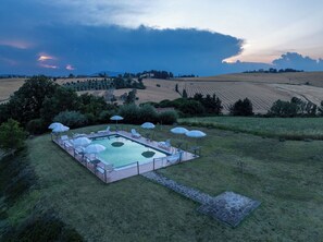 A rectangular outdoor pool with lounge chairs and umbrellas, surrounded by a grassy area and fields. - Apartment in Castel D'arno with 1 bedrooms sleeps 2 (Castel D'arno)
