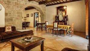 A rustic interior with stone walls, wooden beams, a dining area with a table and chairs, and a cozy seating area with a sofa and a coffee table. - Apartment in Castel D'arno with 1 bedrooms sleeps 2 (Castel D'arno)