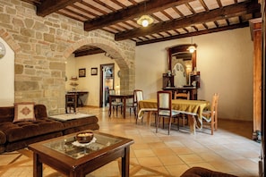 A rustic interior with stone walls, wooden beams, a dining area with a table and chairs, and a cozy seating area with a sofa and a coffee table. - Apartment in Castel D'arno with 1 bedrooms sleeps 2 (Castel D'arno)