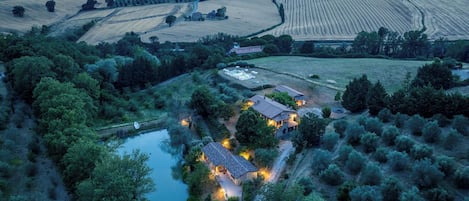 A rural property with multiple buildings, a pond, and surrounding fields.