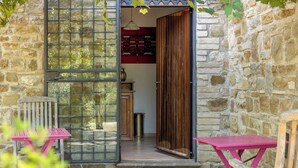 Un edificio in pietra con un'ampia porta in vetro che dà su una stanza con una parete decorata e un armadio in legno.