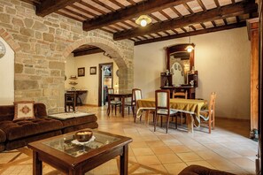 A rustic interior with stone walls, wooden beams, a dining area with a table and chairs, and a cozy seating area with a sofa and a coffee table. - Apartment in Castel D'arno with 1 bedrooms sleeps 3 (Castel D'arno)