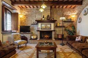 A cozy living room with a fireplace, stone walls, wooden beams, a television, and comfortable seating. - Apartment in Castel D'arno with 1 bedrooms sleeps 3 (Castel D'arno)