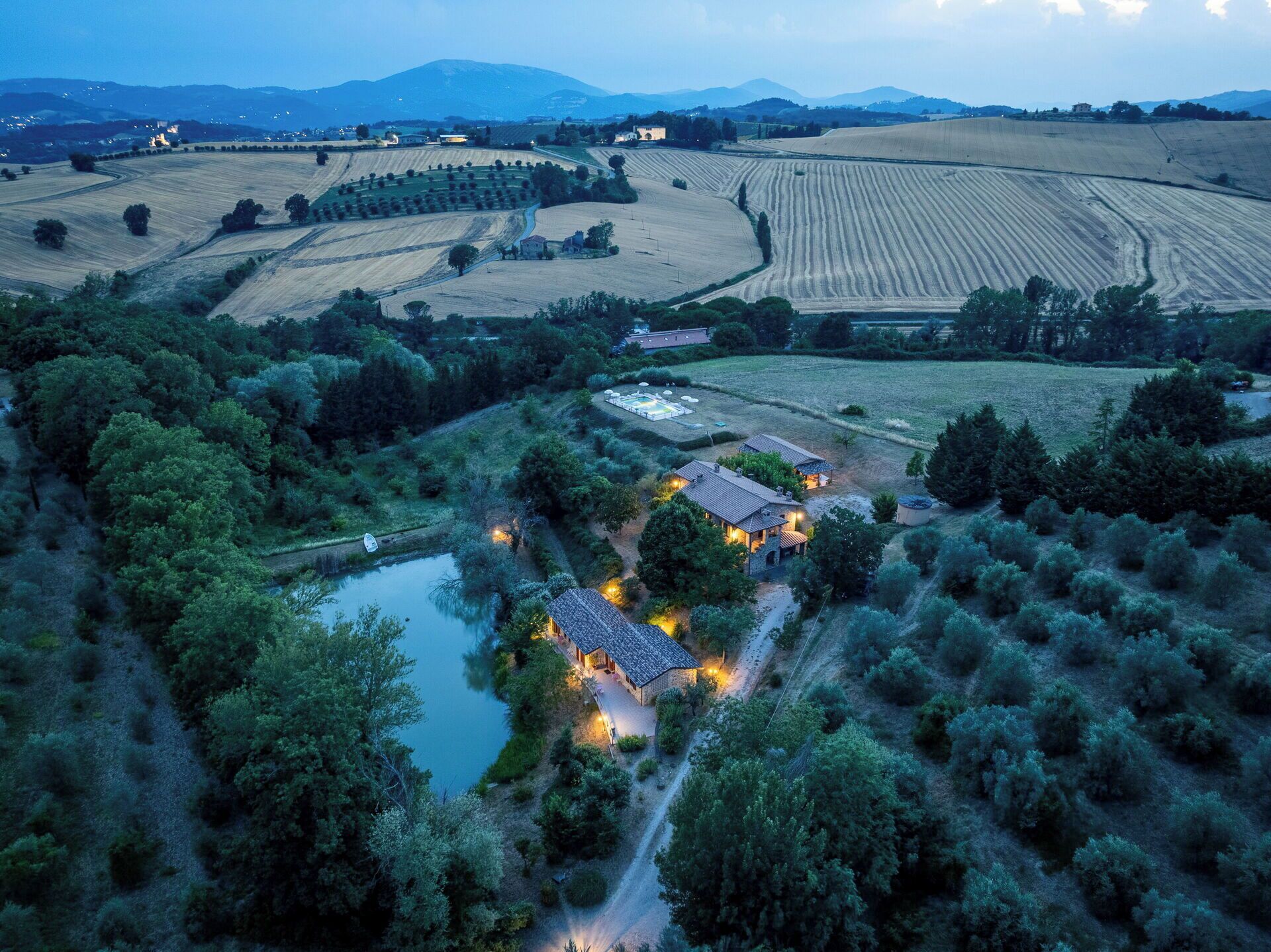 Uma propriedade rural com vários edifícios, um lago e campos ao redor.