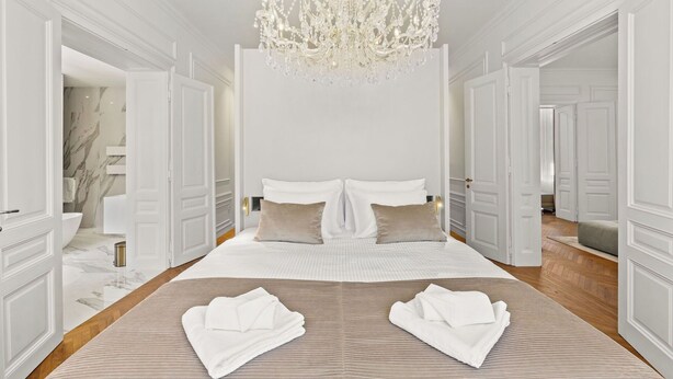 A spacious bedroom with a large bed, a chandelier, and a marble bathroom visible through an open door. - App Nia - Villa Accione (Opatija)