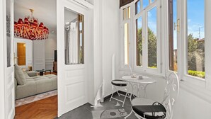 A room with a sofa, a table with chairs, a chandelier, and large windows. - App Nia - Villa Accione (Opatija)
