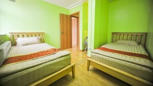 A room with two single beds, wooden headboards, a wooden floor, and a door leading to another room. - Mongolian Vision Tours (Ulaanbaatar)