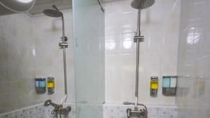 A bathroom with a glass shower enclosure, a bathtub, and tiled walls. - Mongolian Vision Tours (Ulaanbaatar)