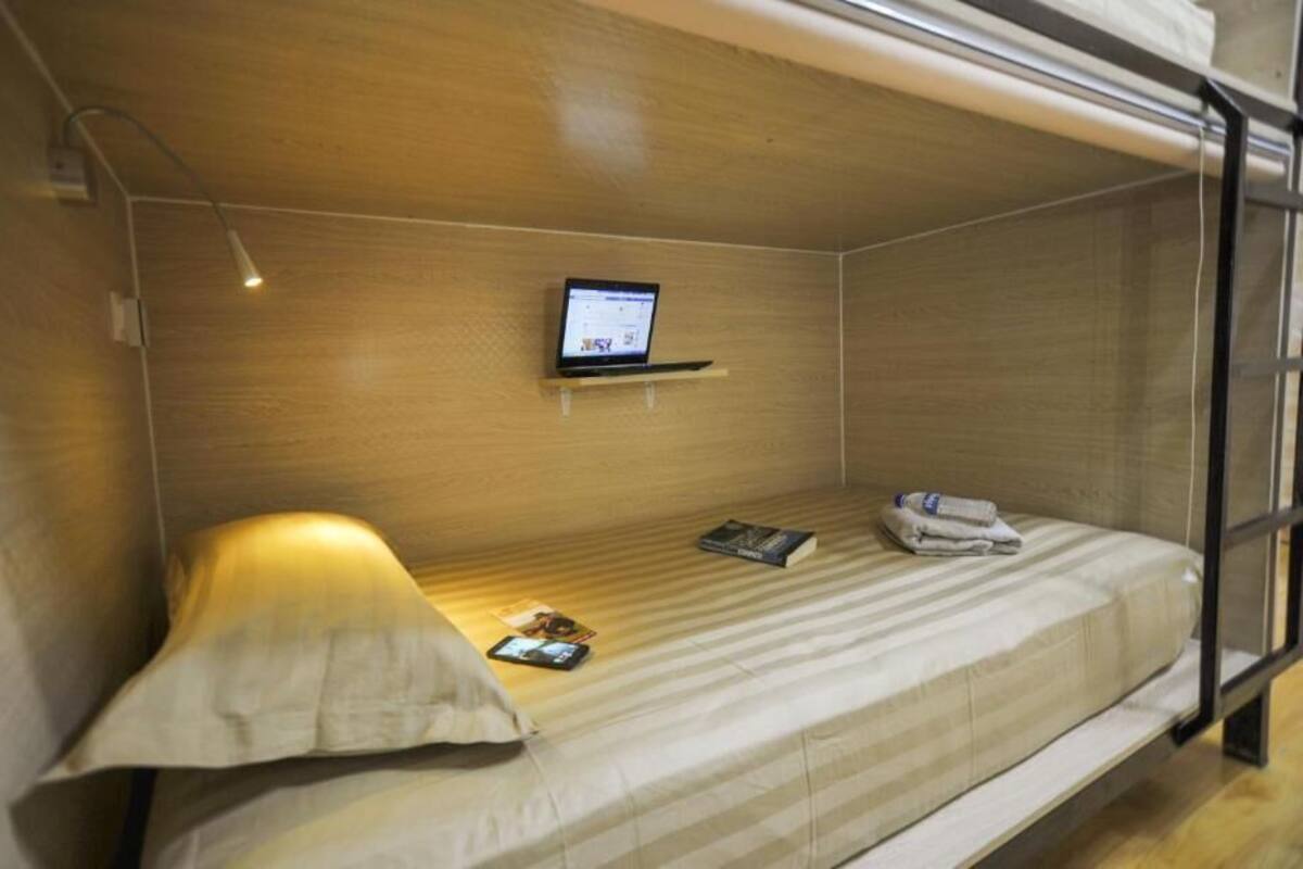 A bunk bed with a laptop on the upper bunk, a pillow, and a folded towel on the lower bunk.