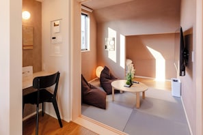 Un espace de vie compact comprenant un bureau, une chaise, un canapé et une petite table agrémentée d’une plante.