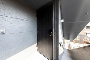 En moderne bygning med en mørk dør, en betonvæg og en rampe til et lavere niveau.