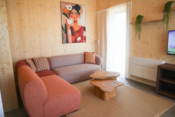 A living room with a sofa, a coffee table, a TV, and a painting on the wall.