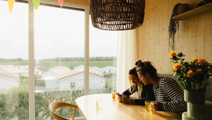 Un comedor con un ventanal amplio, una mesa de madera y una lámpara colgante.