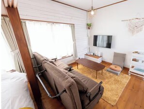 Un soggiorno moderno con un divano, un tavolino, una TV e una pianta.