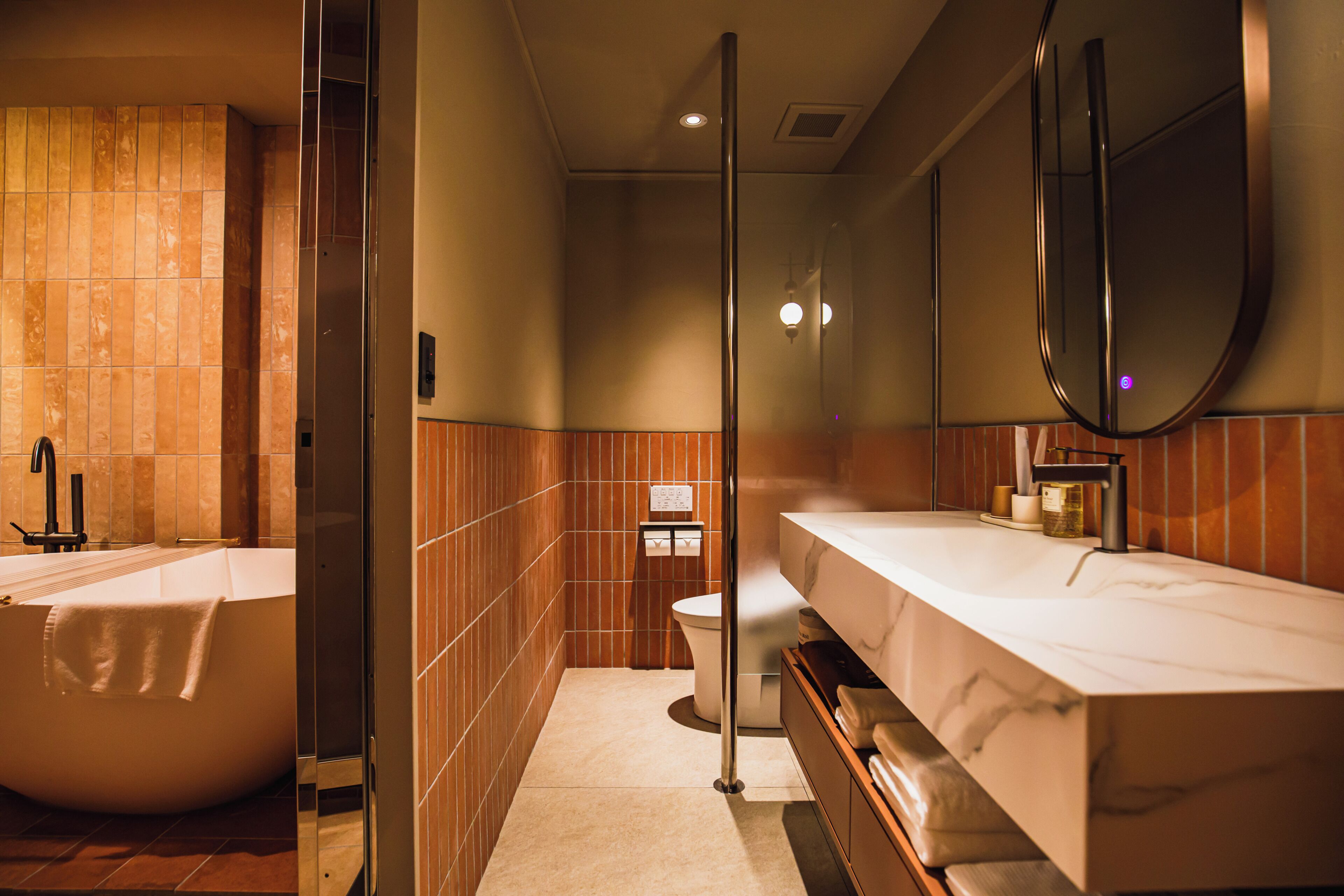 A modern bathroom with a freestanding bathtub, a large mirror, and a vanity with a marble countertop.
