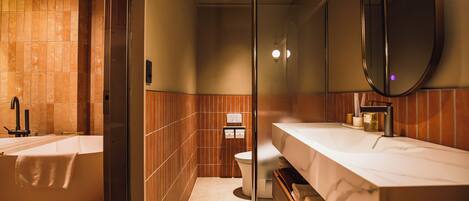 A modern bathroom with a freestanding bathtub, a large mirror, and a vanity with a marble countertop.