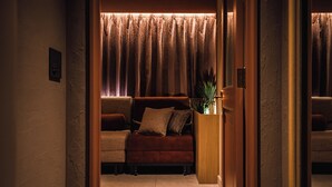 A cozy living room with a sofa, a small table, and a potted plant. - SABLIER by R HOTEL (Osaka)