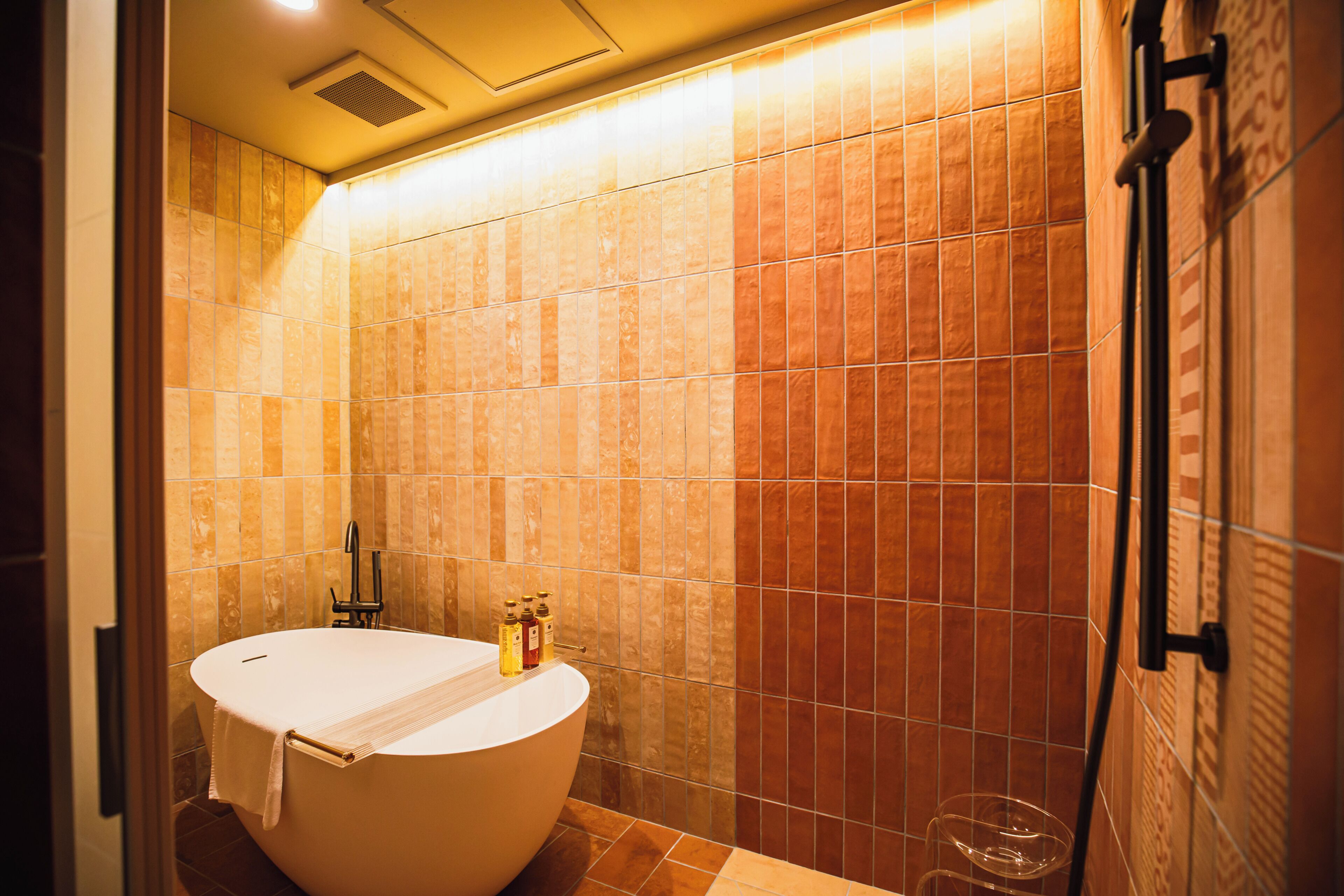 A bathroom with a freestanding bathtub, a towel rack, and a shower area.