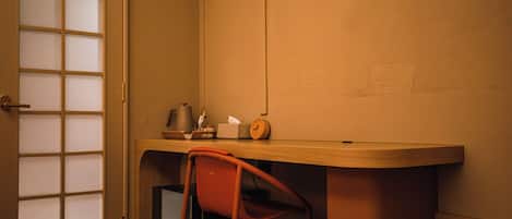 A room with a wooden desk, a chair, a clock, and a door with frosted glass panels.