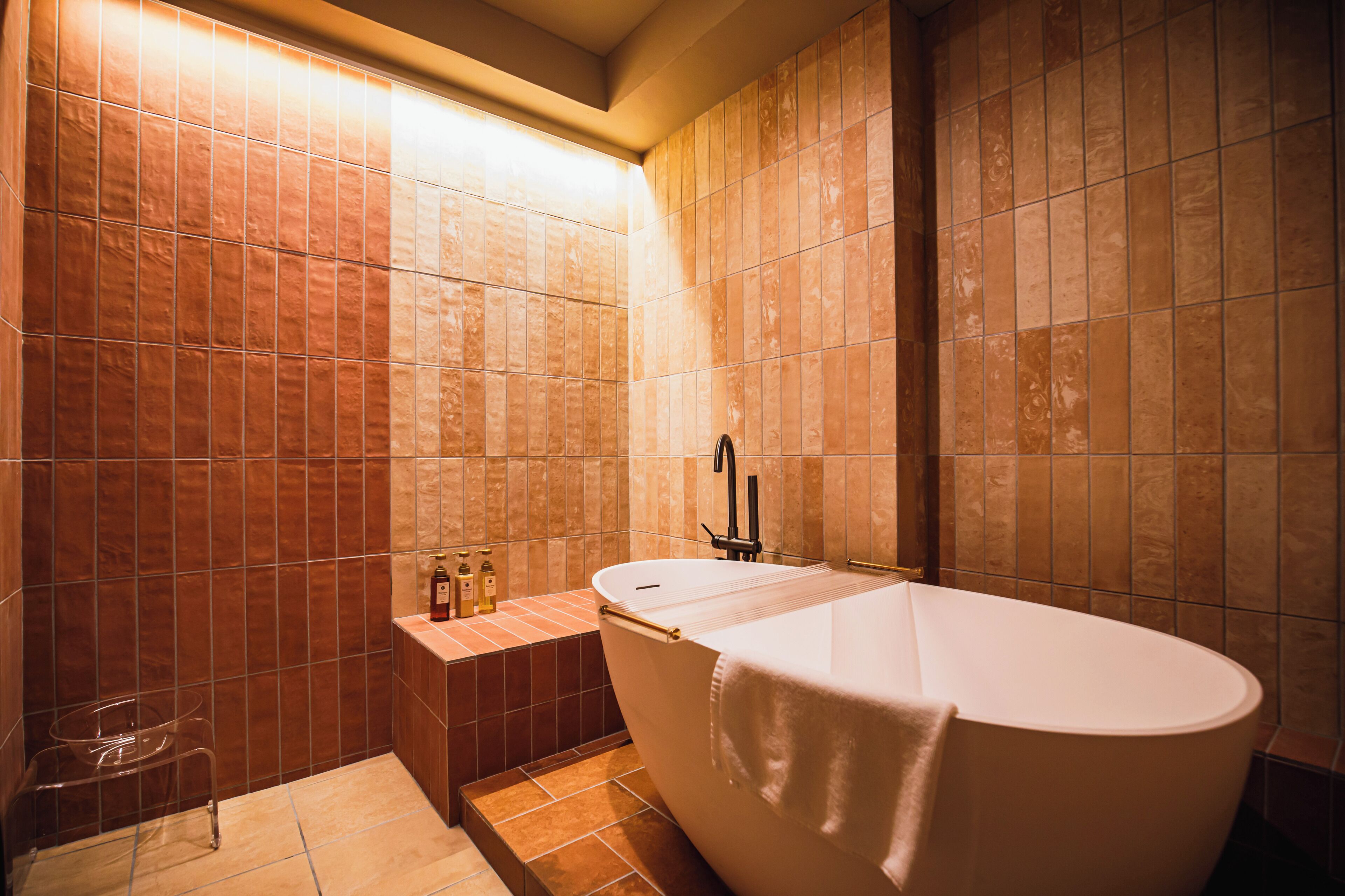 Ein Badezimmer mit freistehender Badewanne, einem Waschbecken und einem kleinen Hocker.