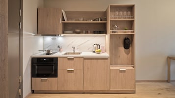 Una cocina moderna con armarios de madera, horno integrado, pileta y una encimera con diversos utensilios de cocina.