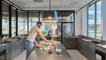 Una cocina moderna con una isla central, electrodomésticos de acero inoxidable y ventanas amplias.