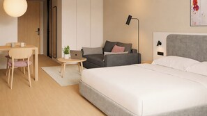 A modern hotel room with a bed, a desk, a chair, a sofa, a small table with a plant, and a lamp. - Stey Stavanger (Stavanger)