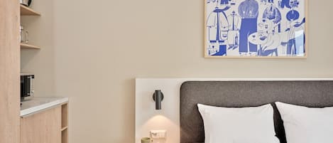 A hotel room with a bed, bedside table, and a wall-mounted artwork.