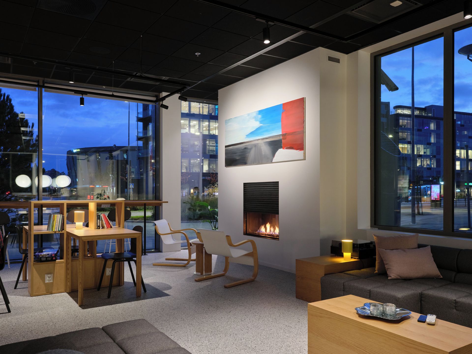 A modern interior with a fireplace, seating area, and large windows offering a city view.