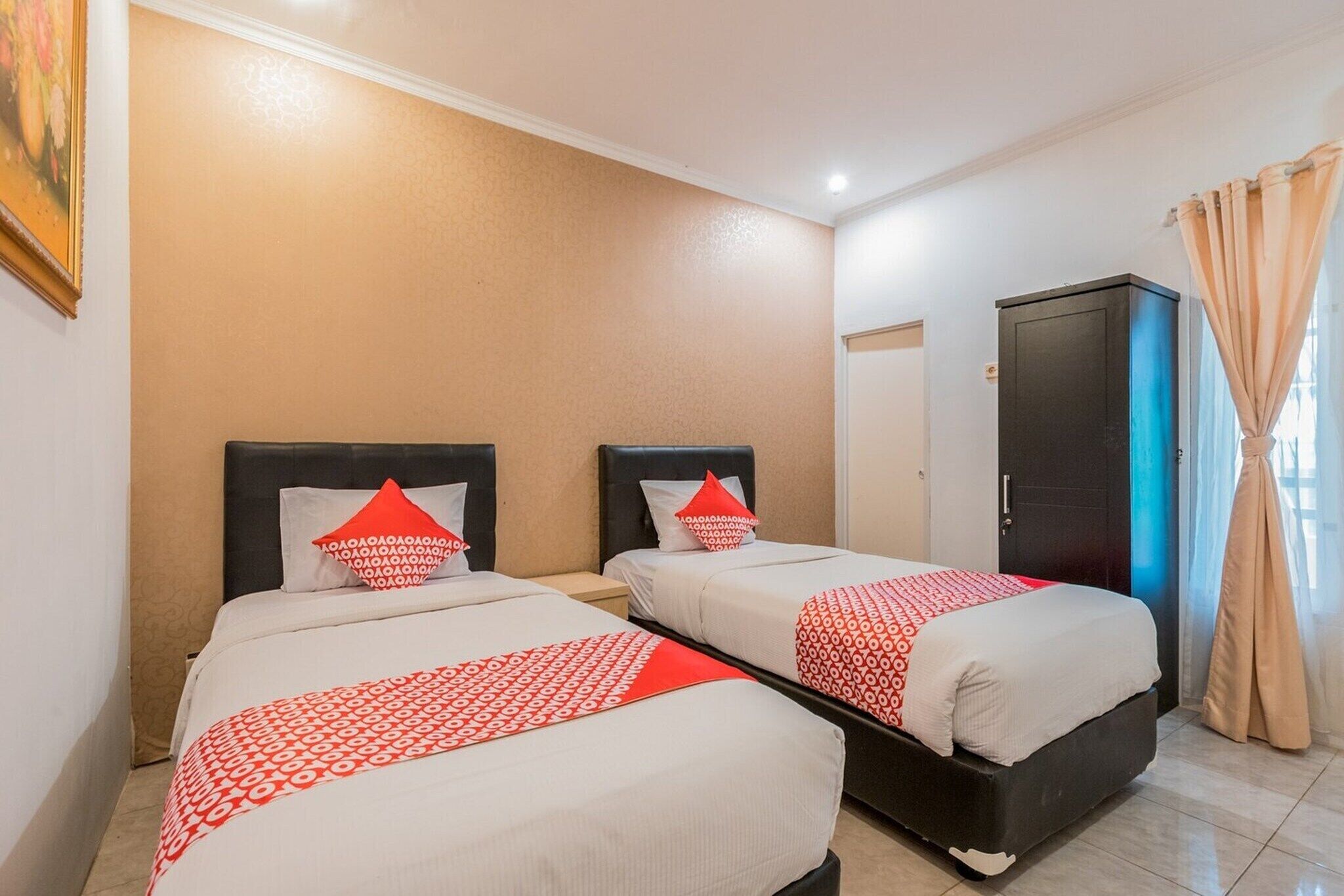 A hotel room with two beds, a wardrobe, and a door.