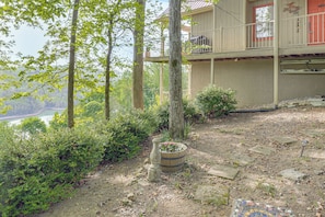 Un immeuble à plusieurs étages doté d’un balcon, entouré d’arbres et agrémenté d’un jardin avec un bac à fleurs en bois.