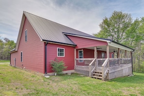 Une grange rouge avec un porche abrité et un escalier en bois.