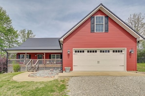 A red single-story house with a white garage, a covered porch, and a gravel driveway. - 3 Mi to Nolin Lake Boat Ramp! Family Home w/ Deck (Mammoth Cave)