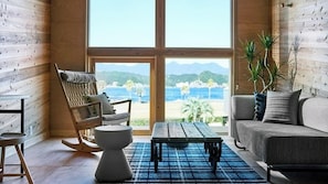 A room with a view of the beach, a rocking chair, a sofa, and a coffee table.