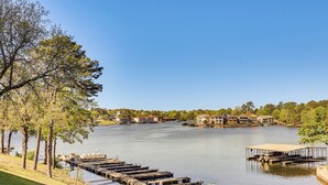Une vue sur le lac, avec des bateaux amarrés, une zone herbeuse et des bâtiments en arrière-plan.