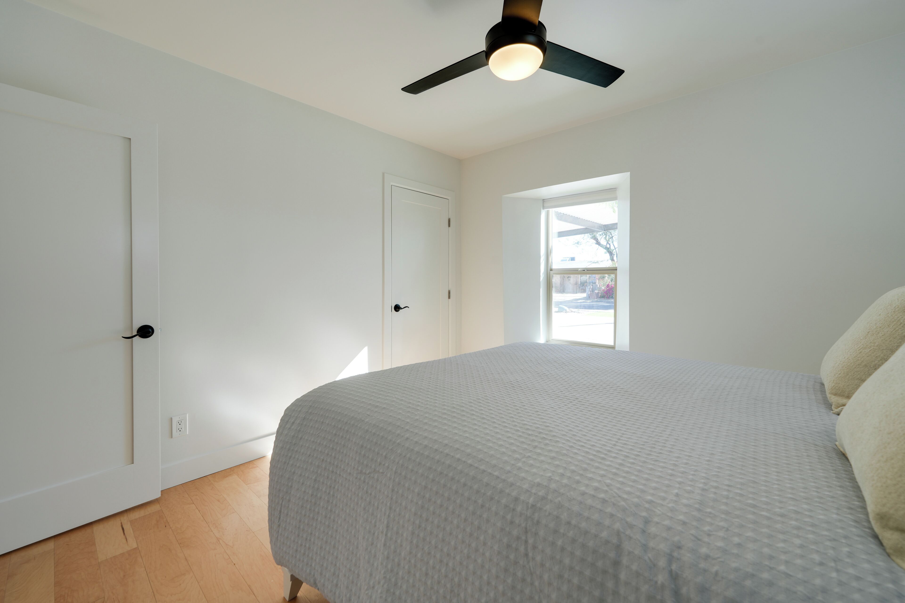 Un dormitorio con cama, ventilador de techo, puerta y ventana.