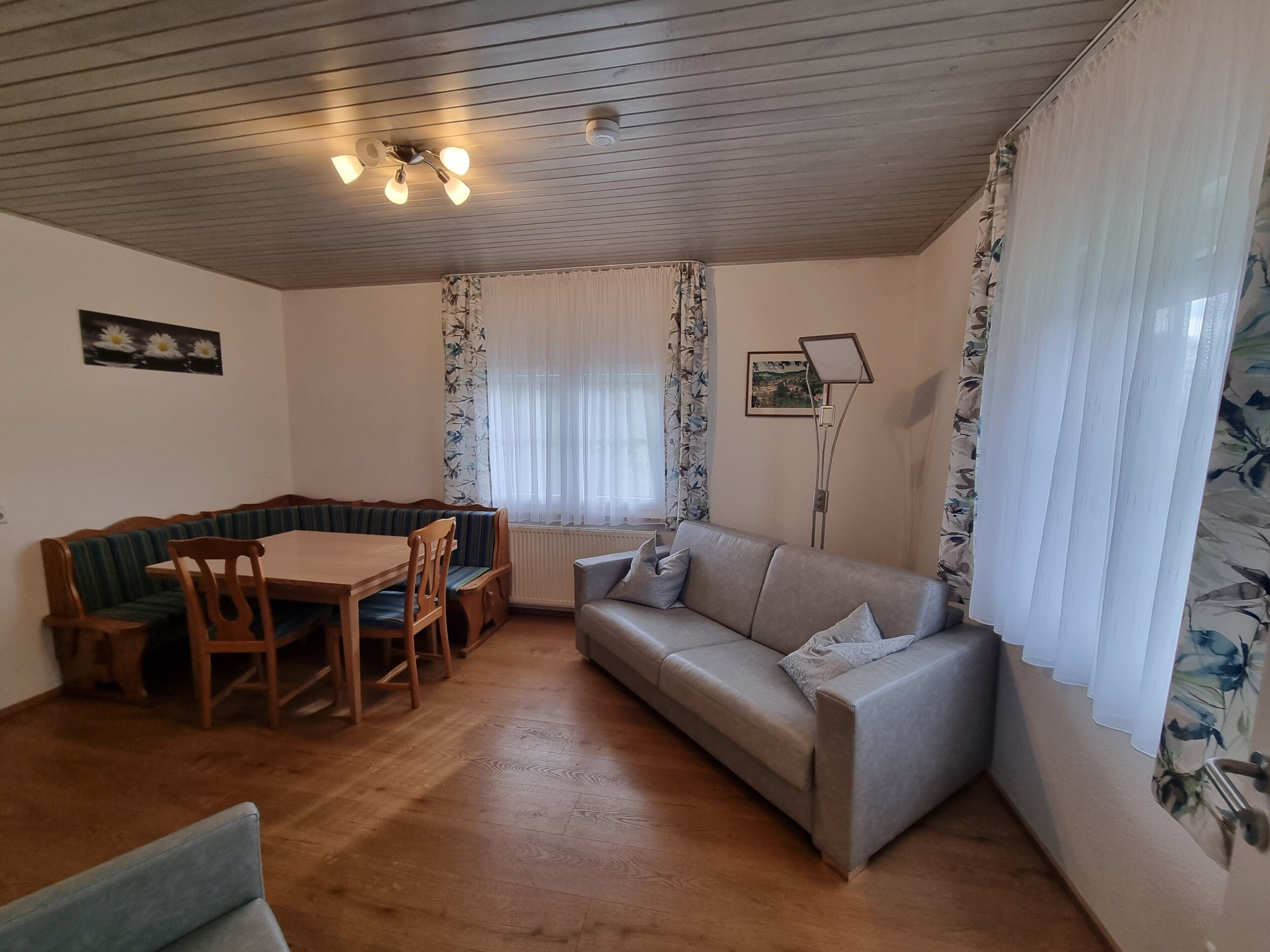 Una habitación con una mesa de comedor de madera, un sofá, un banco y una lámpara de pie.