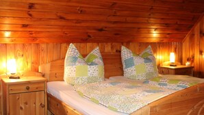 Un dormitorio de cabaña de madera con una cama, dos mesitas de noche y dos lámparas.