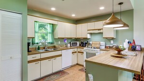 A kitchen with white cabinets, a wooden countertop, a microwave, a stove, and a hanging pendant light. - Private Yard, Lanai! Pet-Friendly Fort Pierce Home (Fort Pierce)