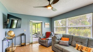 A living room with a gray sofa, a recliner, a flat-screen TV mounted on the wall, and a ceiling fan. - Private Yard, Lanai! Pet-Friendly Fort Pierce Home (Fort Pierce)