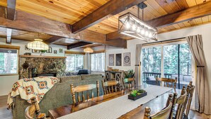 Interior acogedor de una cabaña con una mesa de comedor, sillas de madera, un sofá y una chimenea.