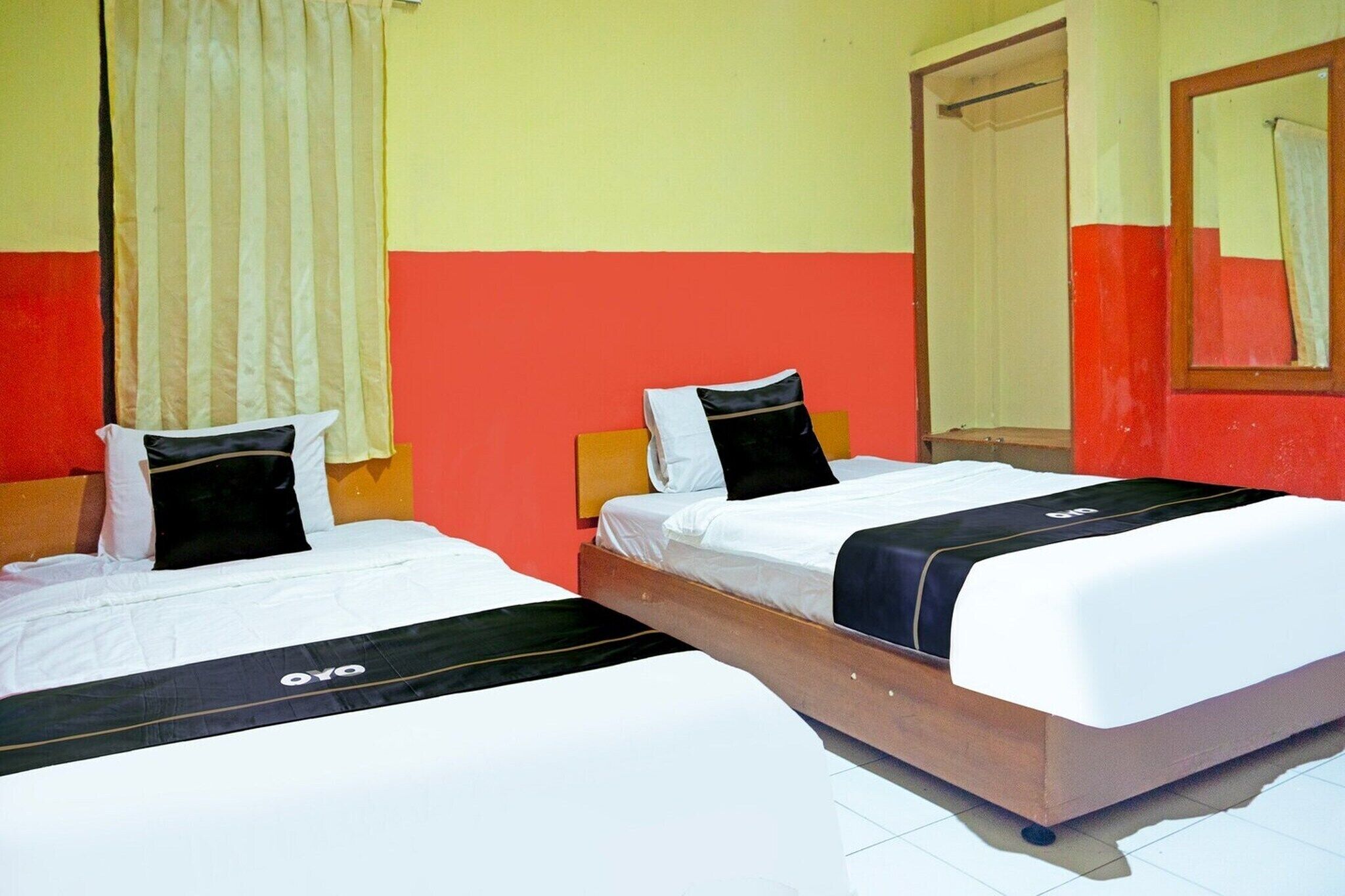 Habitación de hotel con dos camas, un espejo y una ventana con cortinas.