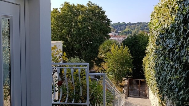 A narrow outdoor corridor with a metal railing, a staircase, and a view of a hillside with trees. - Panoramic sea view apartment in Rab (Palit)